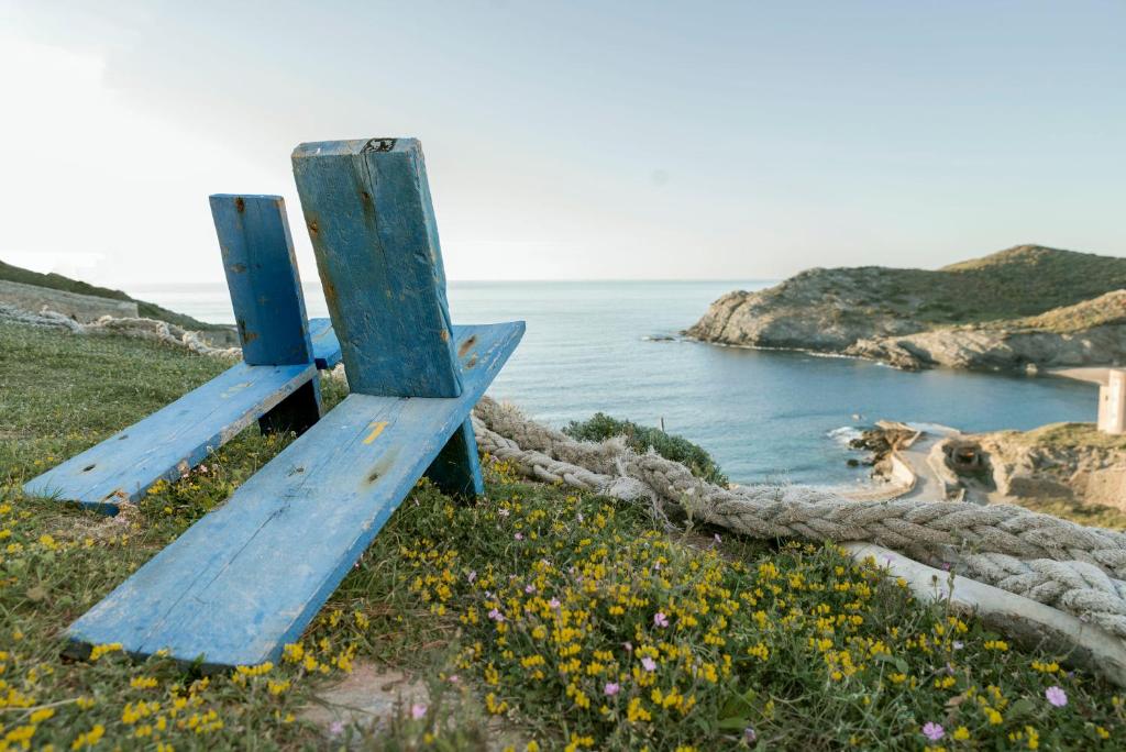 dwie niebieskie ławki siedzące na wzgórzu blisko oceanu w obiekcie Relais Bellavista 5 w mieście Miniera dellʼArgentiera