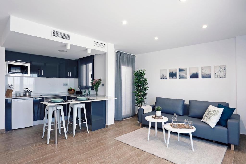 sala de estar con sofá azul y cocina en Rem Apartamentos, en Torre-Pacheco