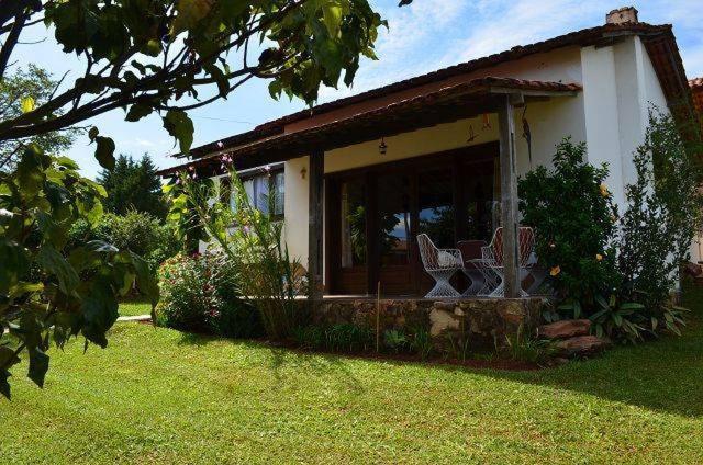 une maison avec une terrasse couverte et 2 chaises dans une cour dans l'établissement Pousada Estação Tiradentes, à Tiradentes