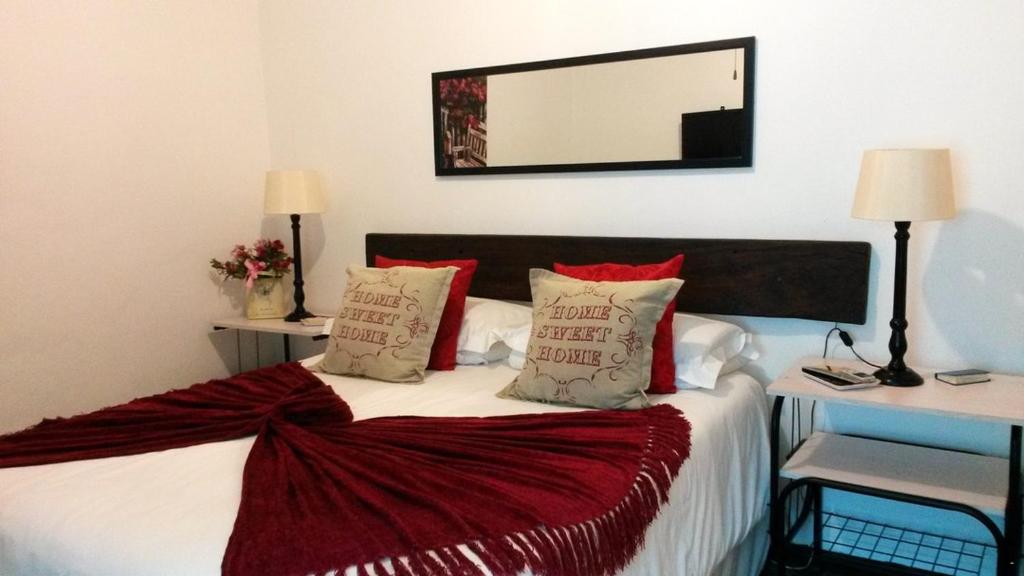 a bedroom with a bed with red pillows and a mirror at DOTJJ B & B in Paarl