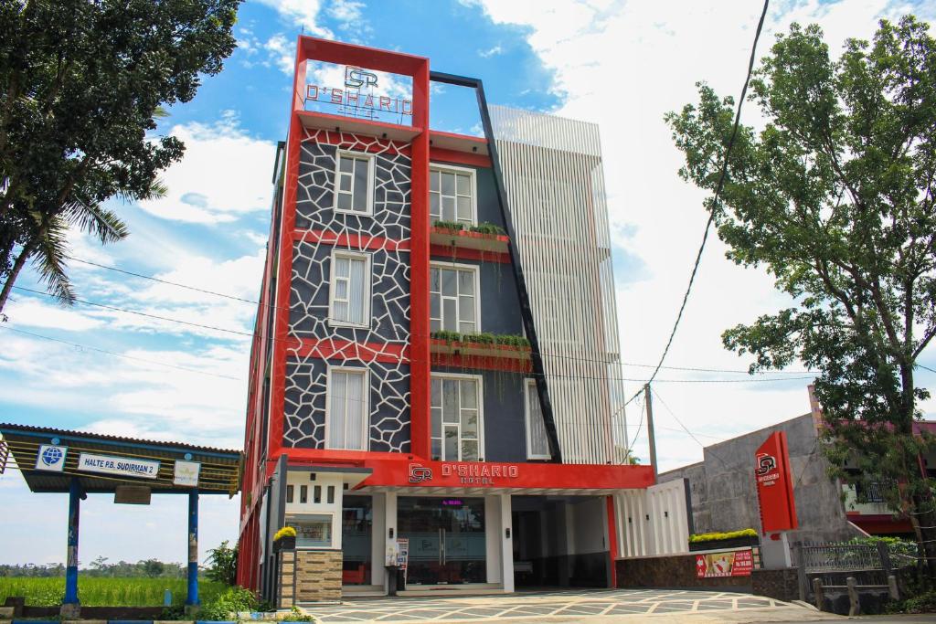 een hoog gebouw met een rode bij D'SHARIO Hotel Kepanjen in Malang