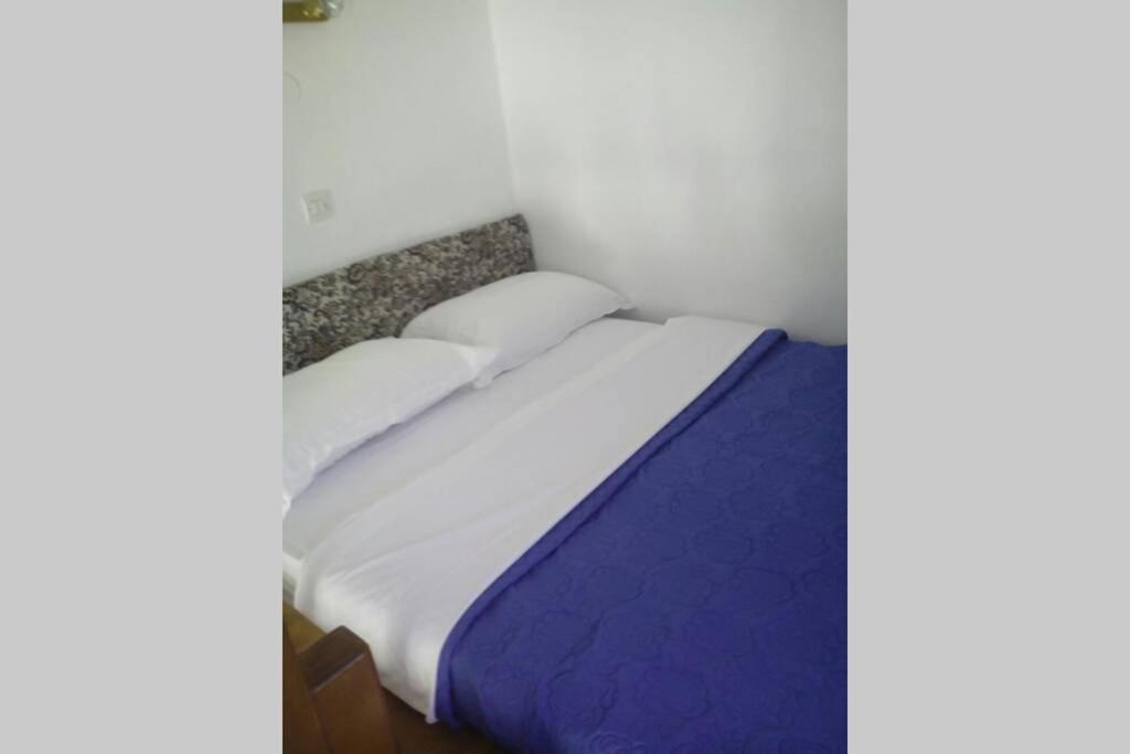 a bed with white sheets and pillows in a room at Sunset Apartment in Patmos