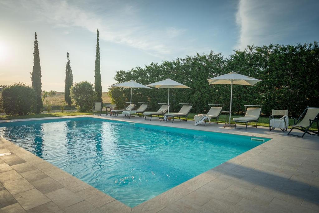 a large swimming pool with chairs and umbrellas at Podere Osteria in Pienza