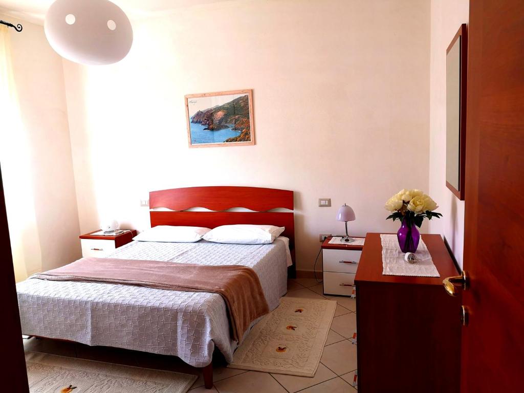 ein Schlafzimmer mit einem Bett und einem Tisch mit einer Blumenvase in der Unterkunft Piccolo B in Bosa