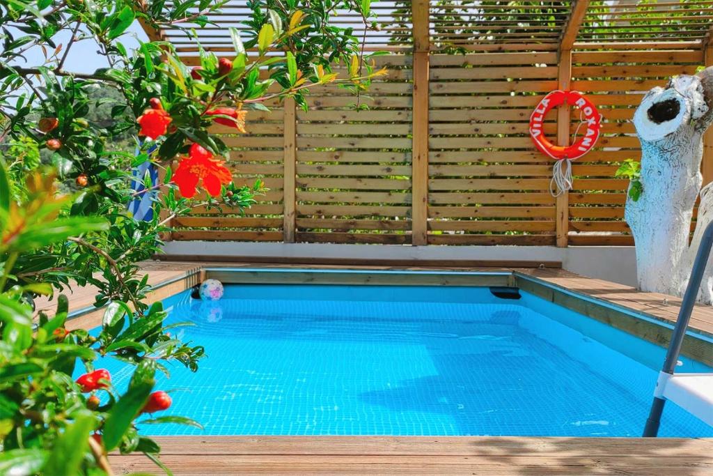a swimming pool in a garden with flowers and a fence at Villa Roxani in Mesklá
