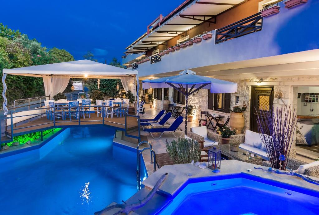 a house with a pool and a patio with tables and umbrellas at Dante's Maisonettes in Amoudi