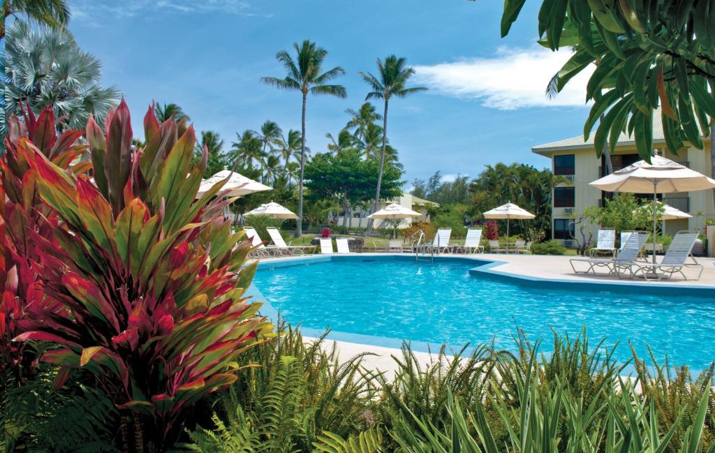 una piscina en un complejo con sillas y sombrillas en Kauai Beach Villas en Lihue