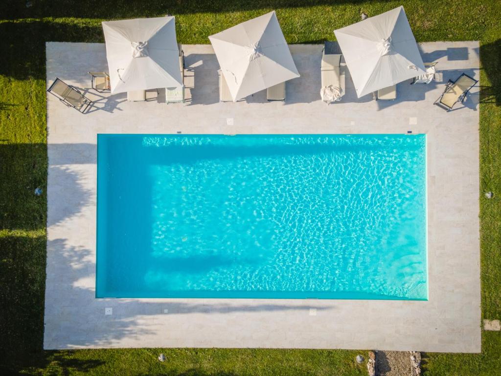 uma vista sobre uma piscina com guarda-sóis brancos em Podere Osteria em Pienza