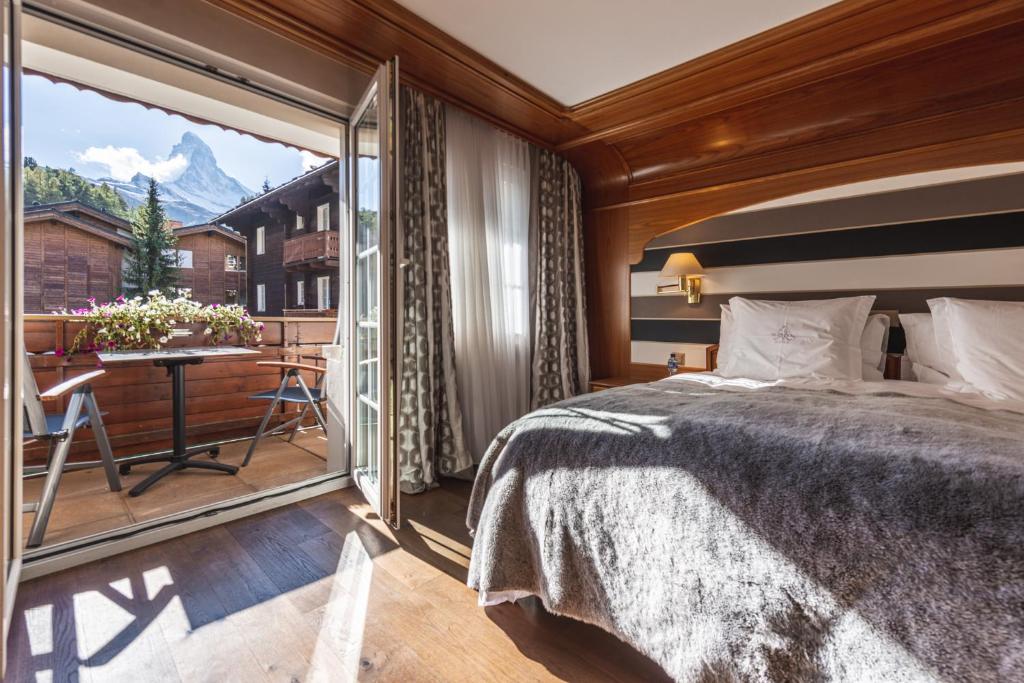 a bedroom with a large bed and a balcony at Boutique Hotel Albana Real - Restaurants & Spa in Zermatt