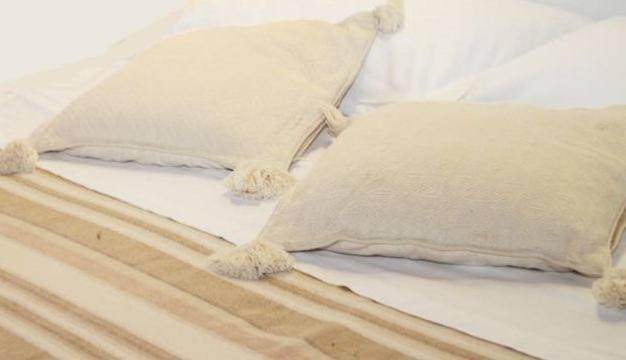 un letto con lenzuola e cuscini bianchi di Cuscino e Cappuccino B&B ad Alghero