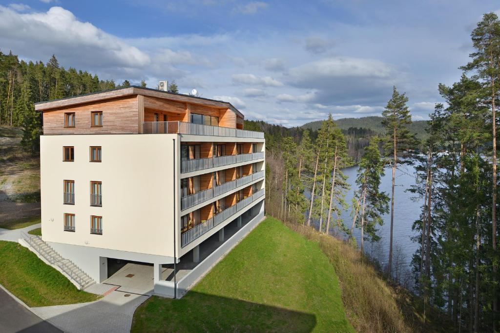 een weergave van een gebouw op een heuvel naast een waterlichaam bij Element Lakeside Apartments in Lipno nad Vltavou