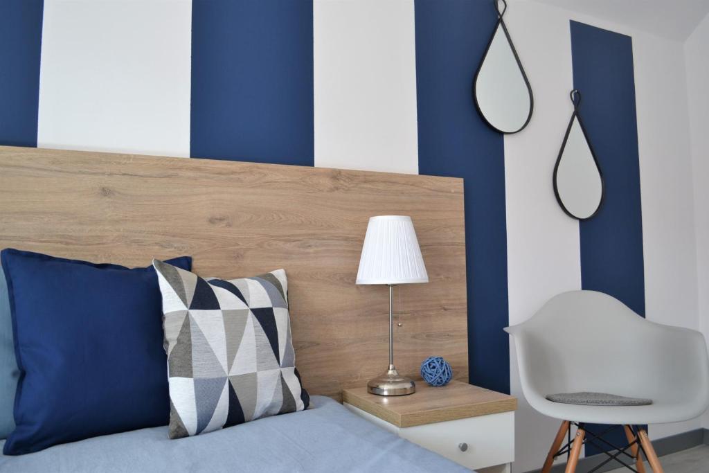 a bed with blue and white walls and a white chair at Międzywodami Jastarnia in Jastarnia