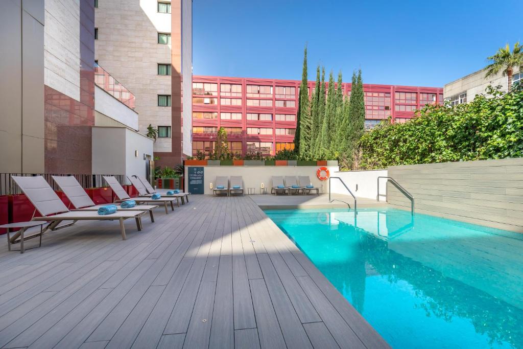 un patio con sillas y una piscina en un edificio en Occidental Sevilla Viapol, en Sevilla