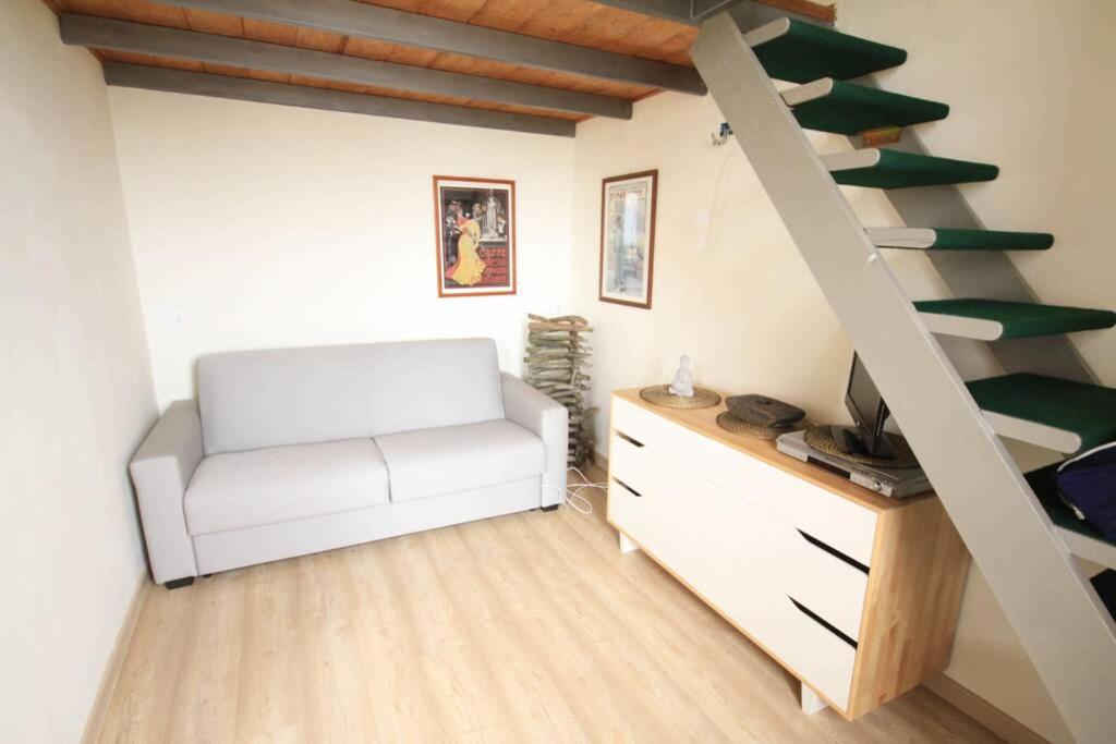 a living room with a white chair and a staircase at Bilocale Fronte Mare in Marina di Pisa