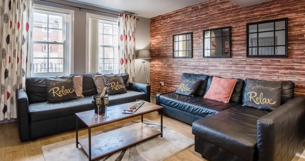 a living room with leather couches and a brick wall at 3 The Gathering Chester Central in Chester