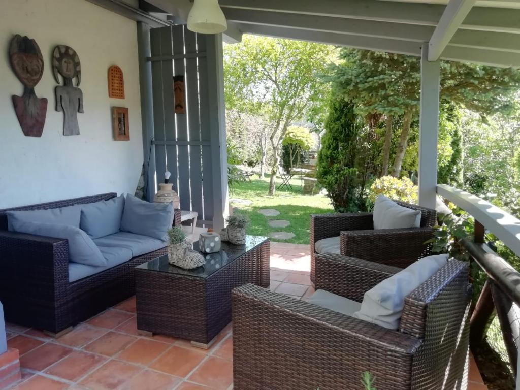patio z wiklinowymi krzesłami i niebieską kanapą w obiekcie El Oteru I w mieście Villaviciosa