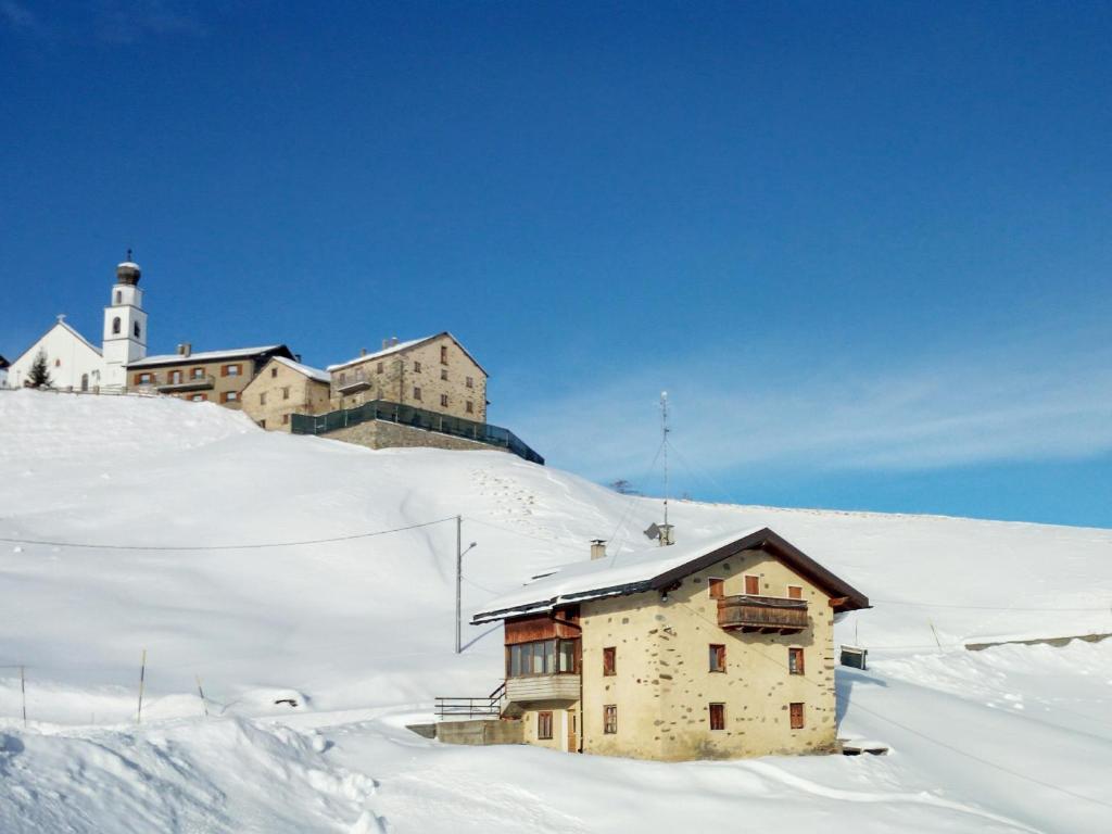 een gebouw op een besneeuwde heuvel met een vuurtoren op de achtergrond bij Casa Rainolter in Livigno