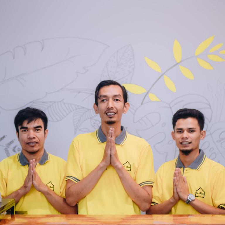 three men standing in front of a table holding their hands up at AUR KUNING HOSTEL SYARIAH Bukittinggi in Bukittinggi