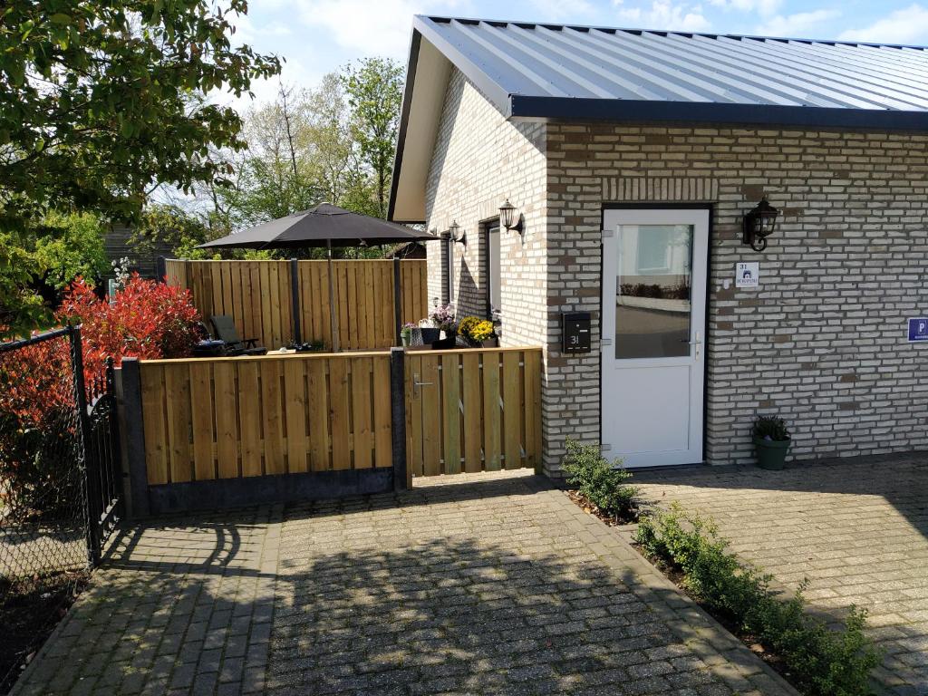 a small house with a wooden fence and a white door at De Kuiperij in Arcen