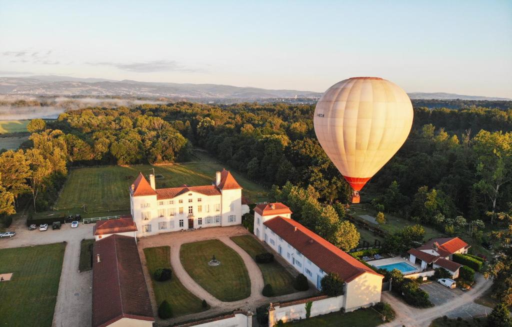 Ein Heißluftballon fliegt über ein Gebäude in der Unterkunft Chateau des Perichons in Poncins
