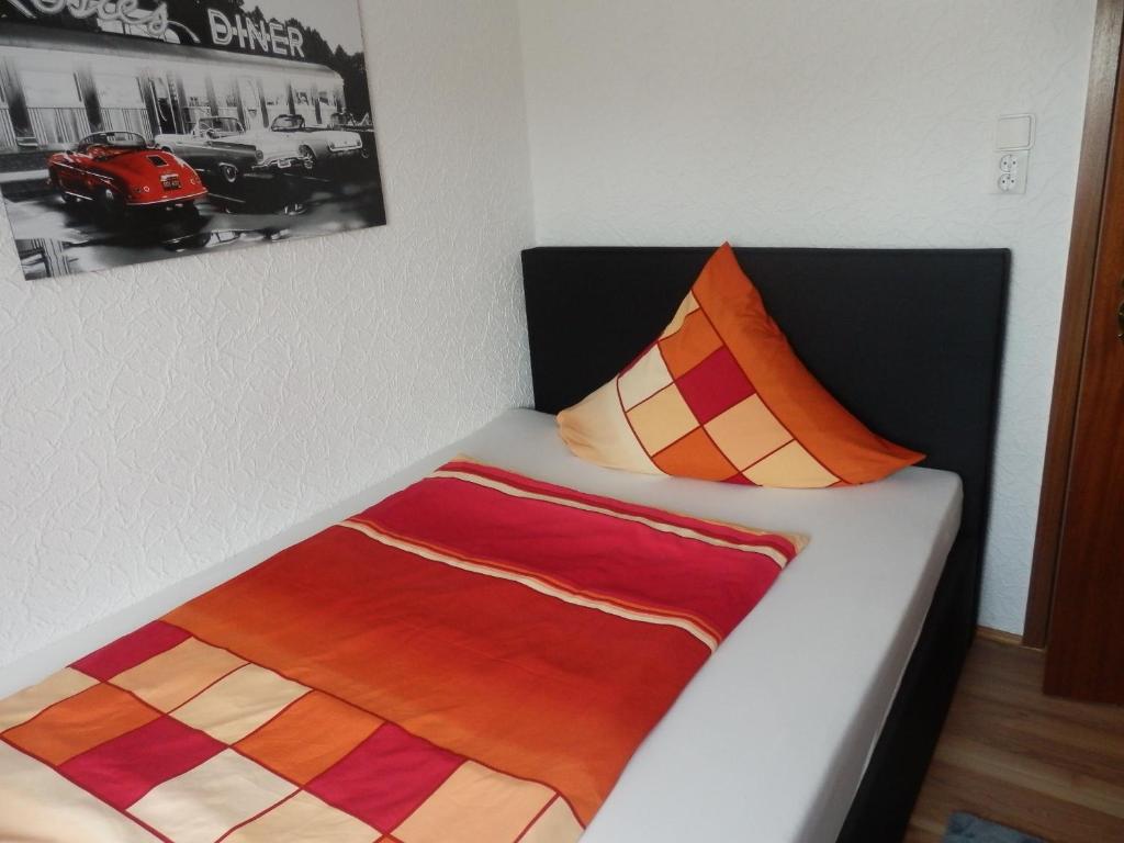 a bed with a comforter and a blanket on it at Gästezimmer Boxenstopp in Veitsbronn
