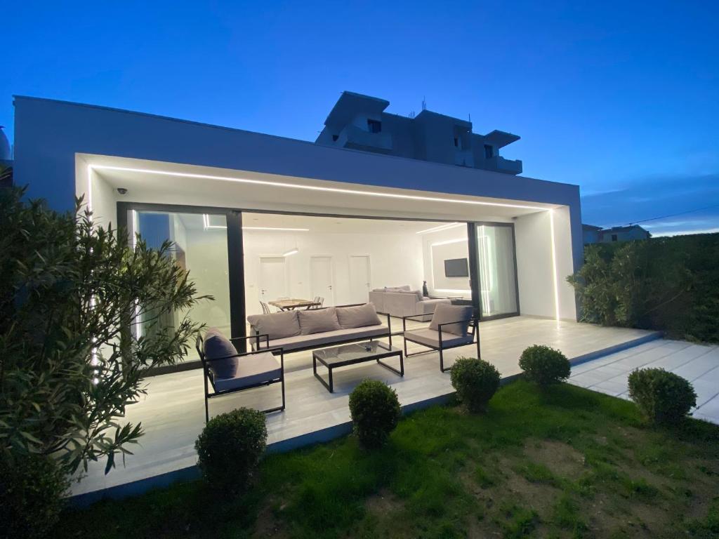 Cette maison dispose d'une terrasse avec un canapé et des chaises. dans l'établissement White Beach Villa 2 - Luxury, à Velipojë