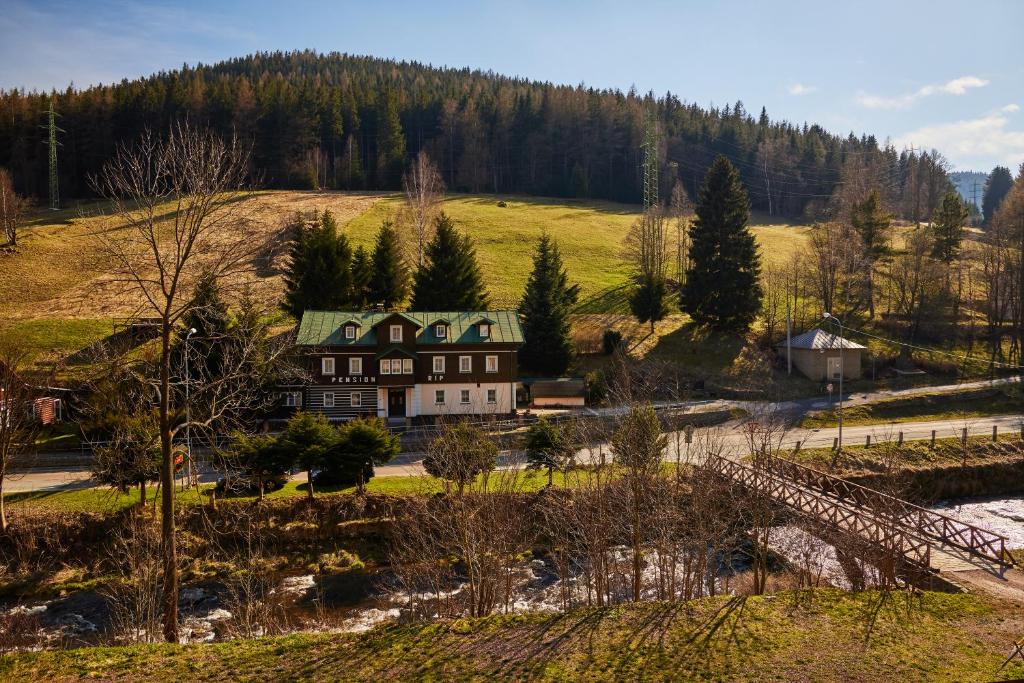 duży dom na wzgórzu z drzewami w tle w obiekcie Pension Říp w mieście Pec pod Sněžkou