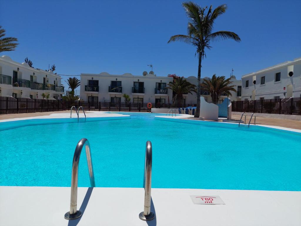 a large blue swimming pool with buildings in the background at Casa Contento by Sea You There Fuerteventura in Corralejo