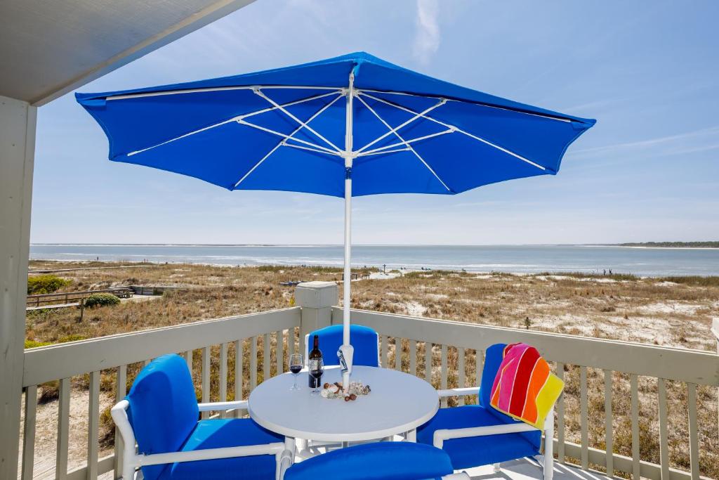 una mesa y sillas con una sombrilla en el balcón en 1314 Pelican Watch - Seabrook Island - Beachfront 5 Star Condo - Fido Friendly, en Seabrook Island