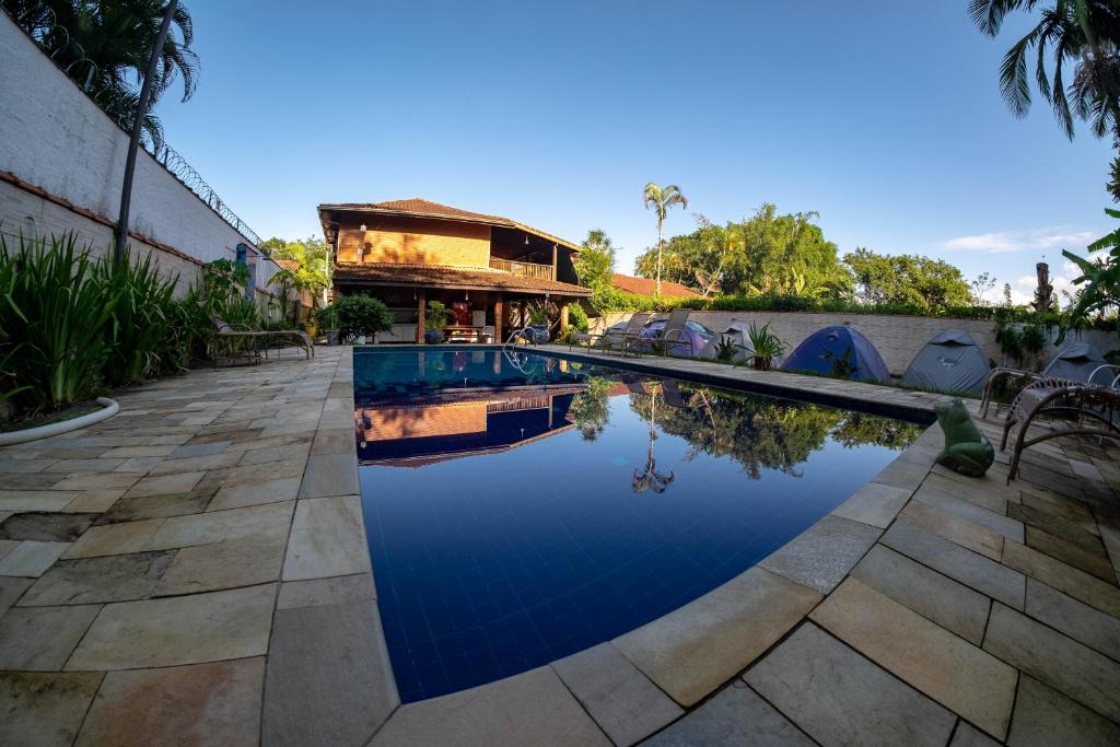 a swimming pool in front of a house at Hostel Trópico de Capricórnio - Vermelha do Centro in Ubatuba