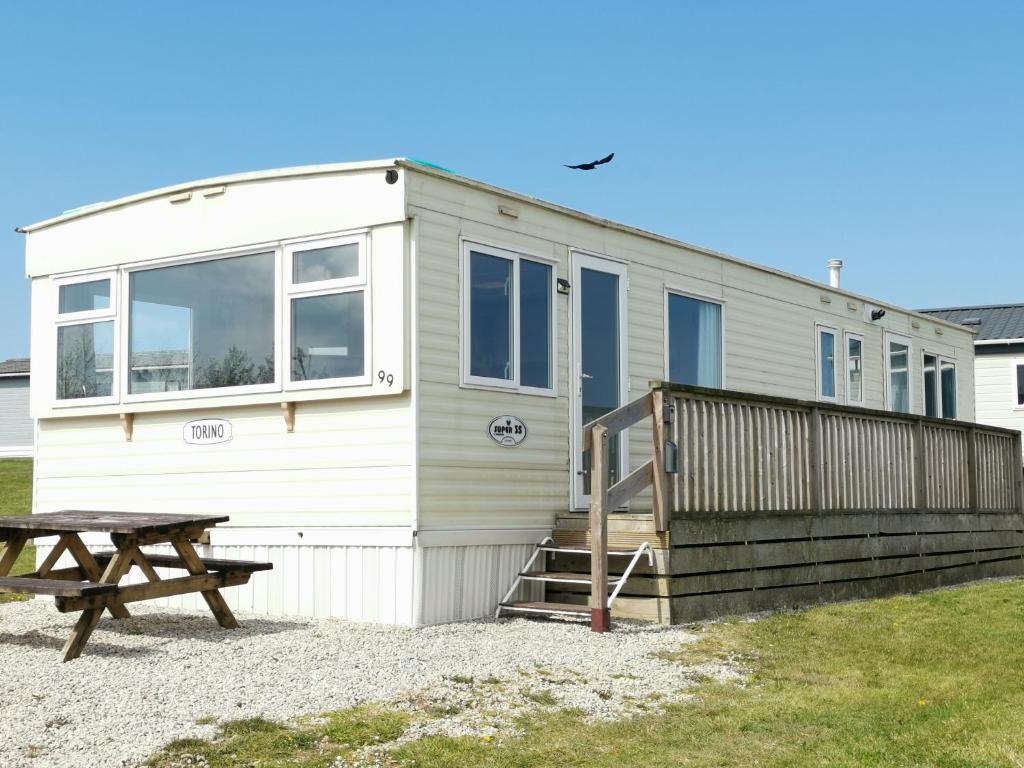 uma pequena casa com uma mesa de piquenique em frente em No99 Static Caravan Widemouth Fields 3 mins from beach em Poundstock