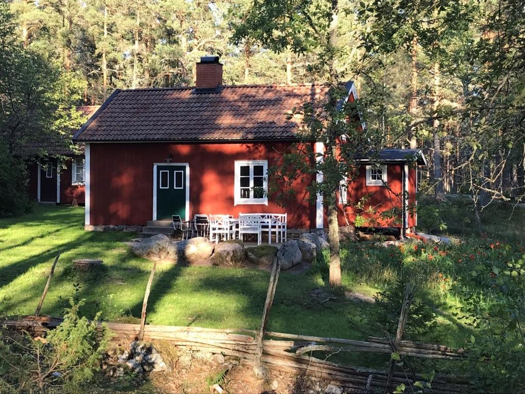 mały czerwony dom na środku podwórza w obiekcie Lilla Stubbetorp w mieście Vimmerby