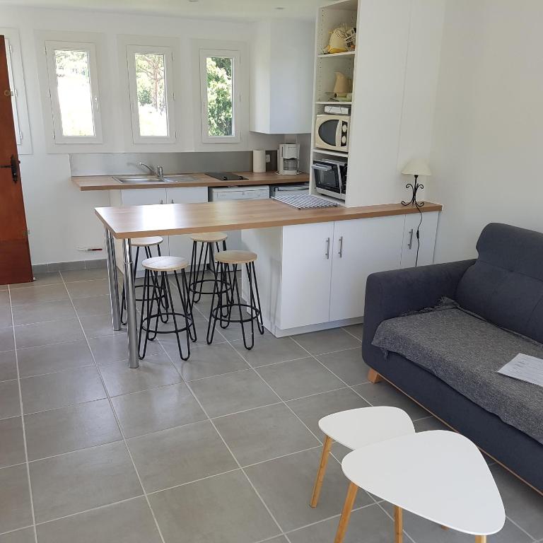 - une cuisine et un salon avec une table et des tabourets dans l'établissement Les Lucioles, à Cavalaire-sur-Mer