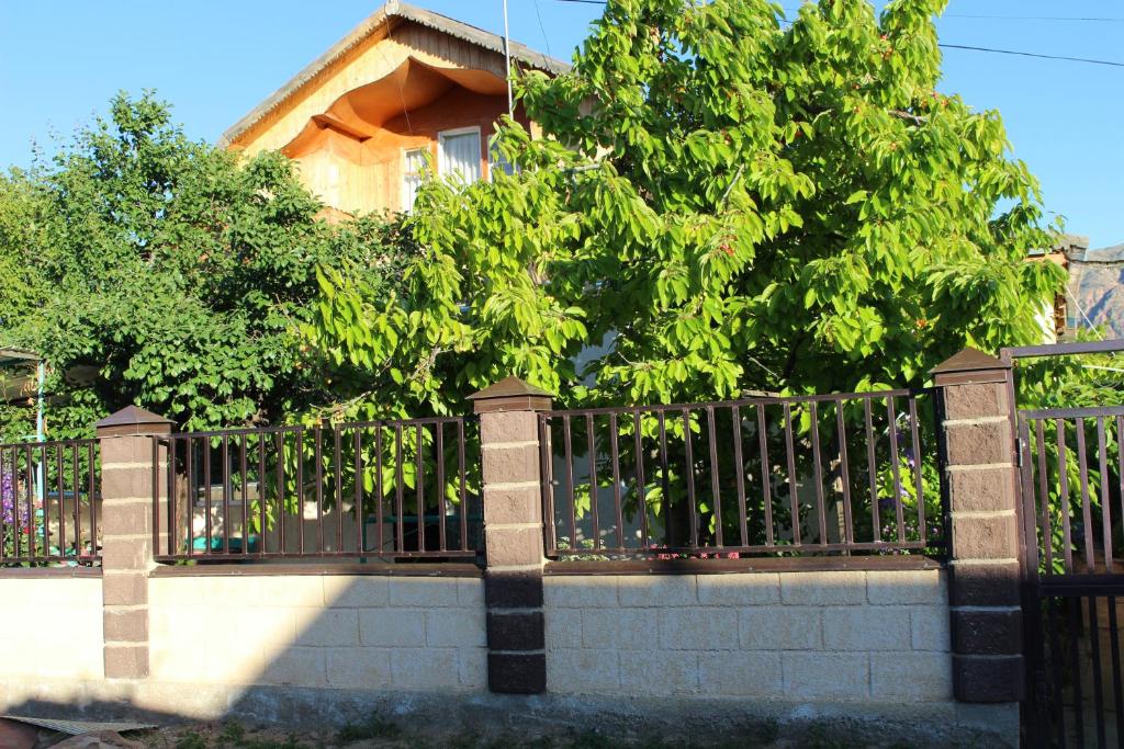 a fence in front of a house with a tree at Guest House Olga in Kaji-Say