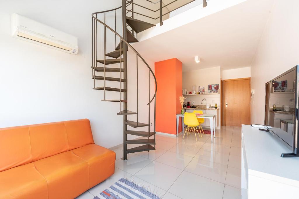 a living room with an orange couch and a spiral staircase at Apartamento Lugar Perfeito Duplex Casemiro 199 in Porto Alegre