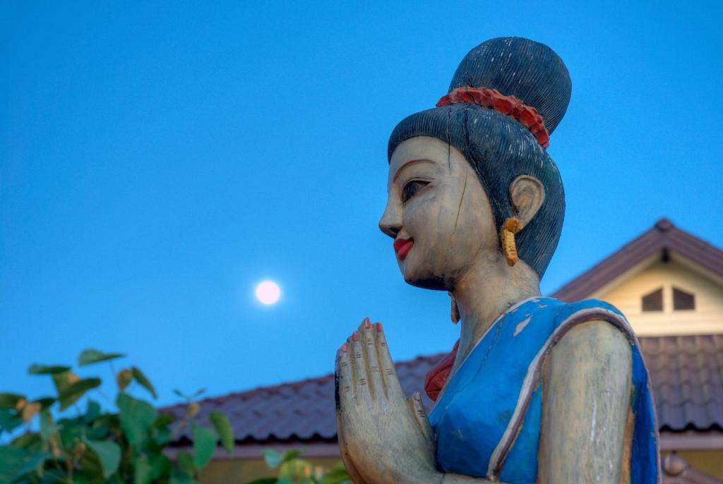 een standbeeld van een vrouw met de maan op de achtergrond bij Maekok River Village Resort in Mae Ai