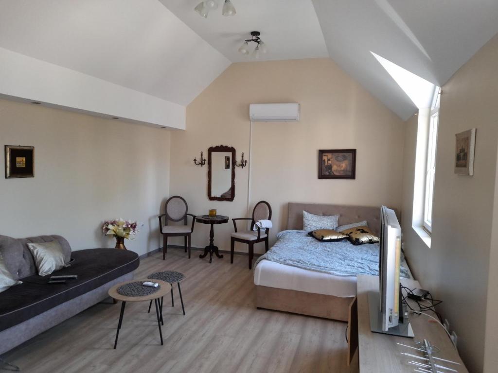 a bedroom with a bed and a couch and a tv at Wanted Šabac apartman in Šabac