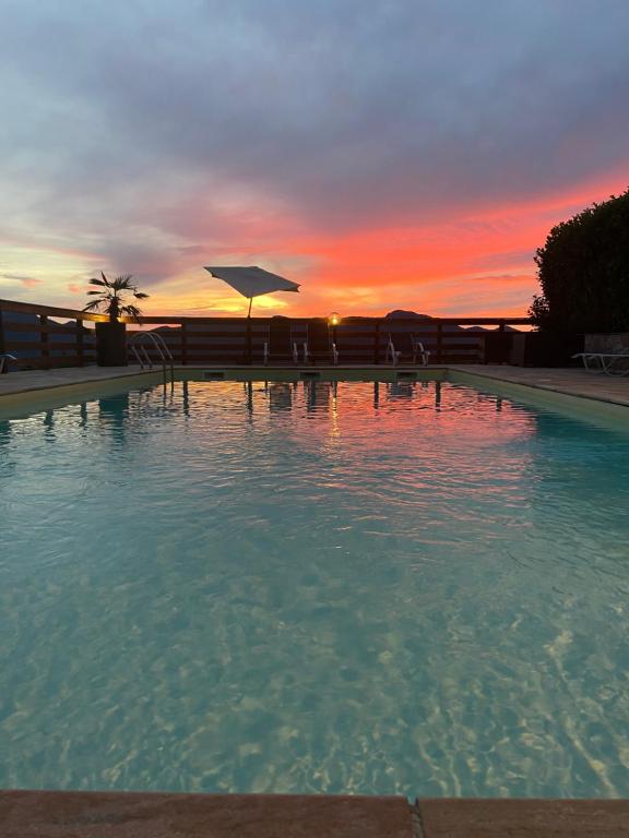 a large swimming pool with a sunset in the background at Logis Hôtel Le Bellevue in Trévignin