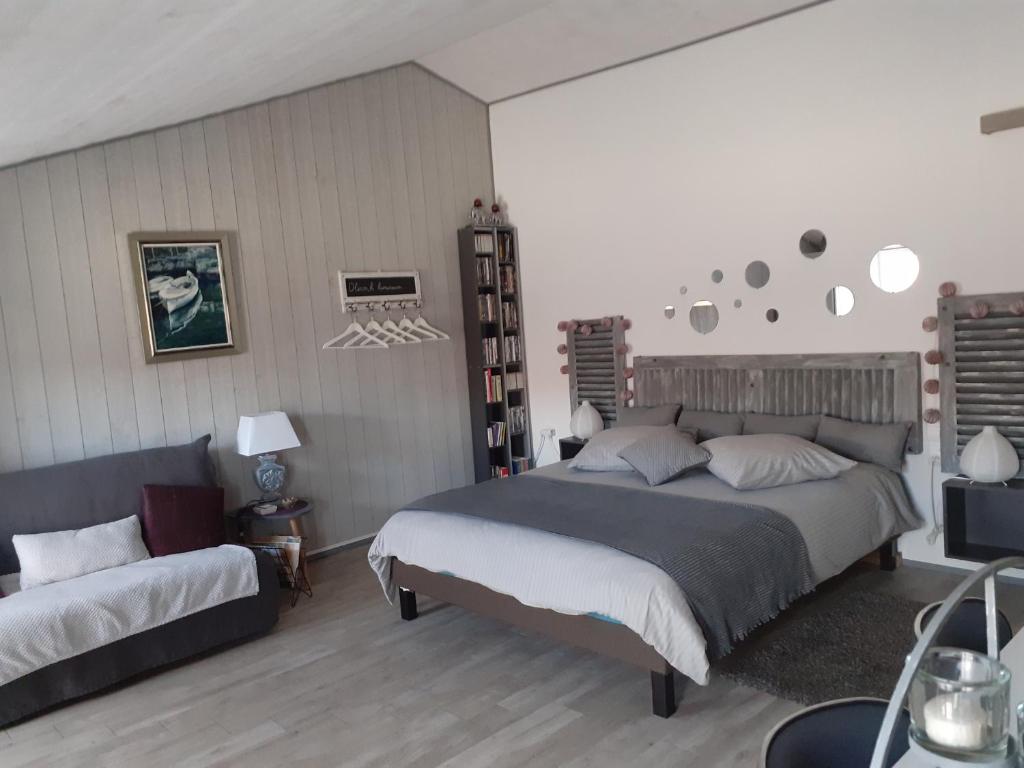 a bedroom with a large bed and a couch at Belle de nuit in Le Trait dʼUnion