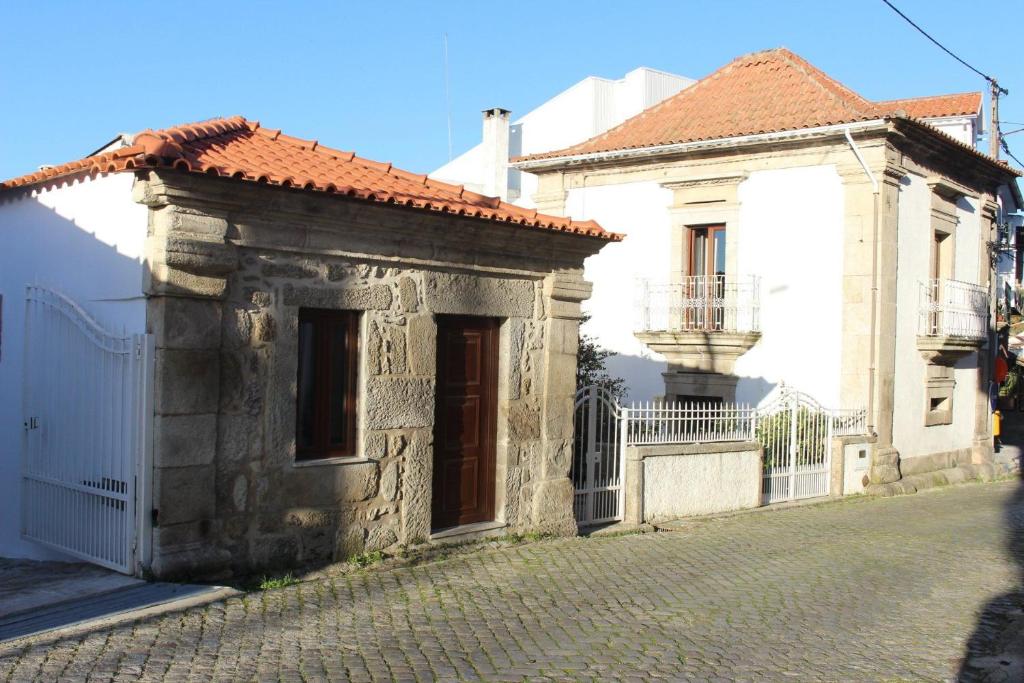 un antiguo edificio en una calle al lado de un edificio blanco en Casa Bento Moura Portugal en Moimenta da Serra