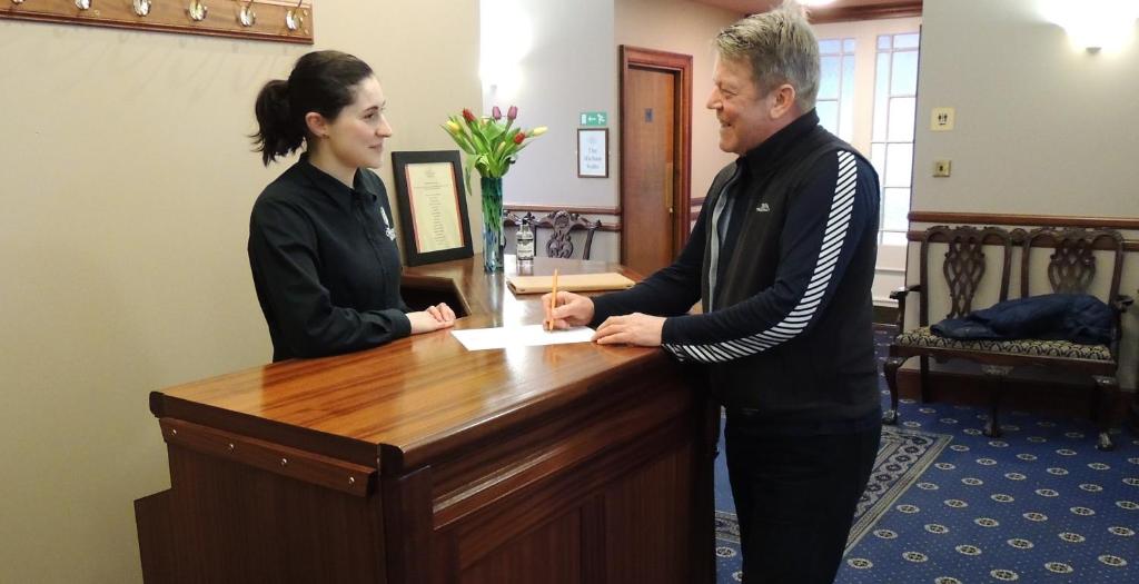 a man and a woman standing at a desk at The Orkney Hotel in Kirkwall