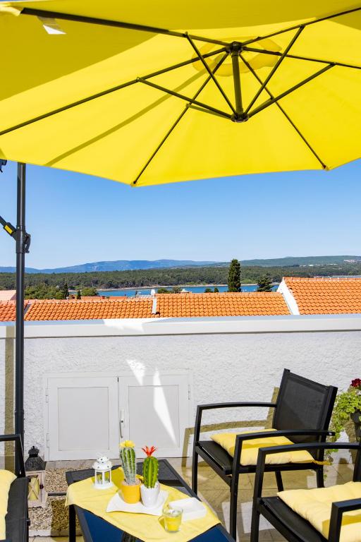 a yellow umbrella on a patio with tables and chairs at The Rooftop Apartment Punat in Punat