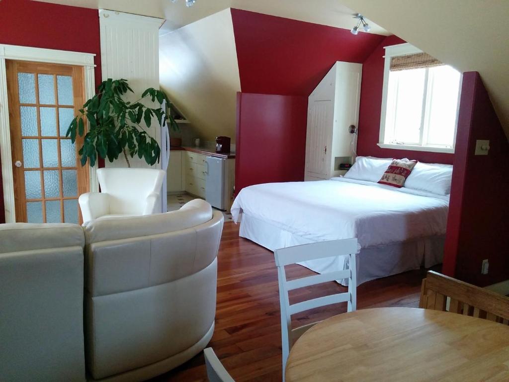 a bedroom with red walls and a bed and a table at Au Cachalot Caché le gîte hôtel in Tadoussac