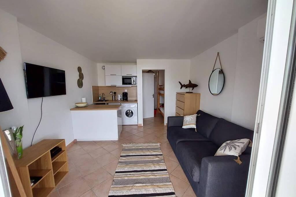 uma sala de estar com um sofá azul e uma cozinha em Magnifique Studio à 50m de la plage de Cavaliere - Studio Tamarindo em Le Lavandou