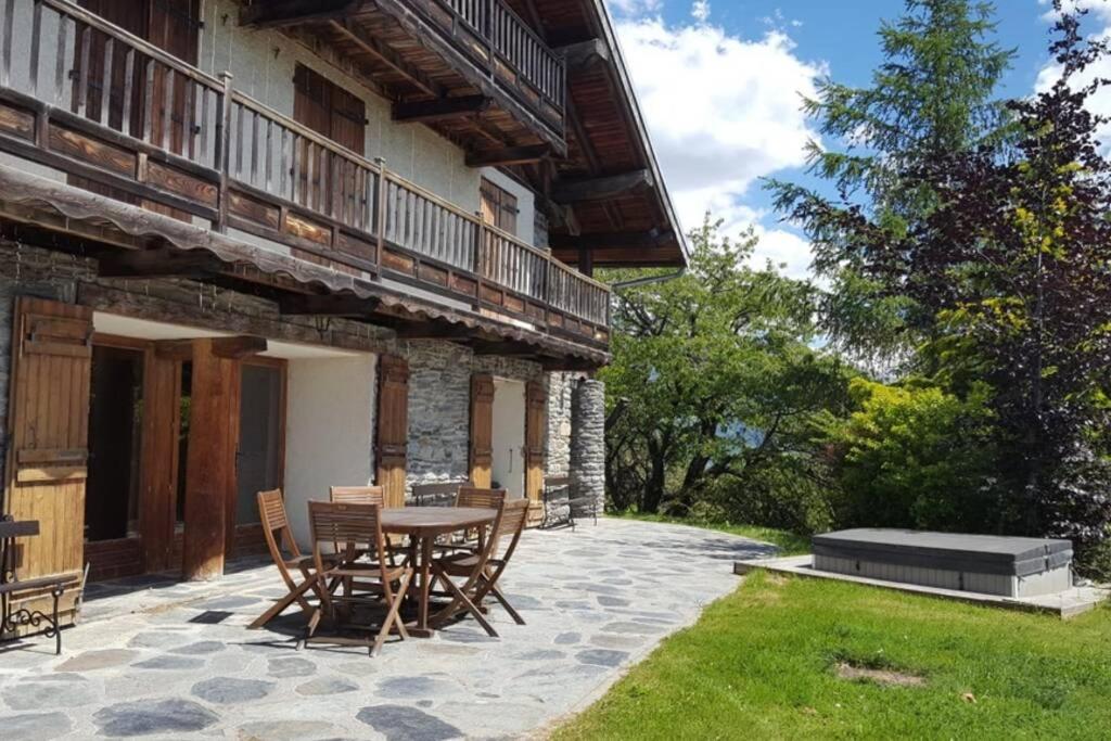 un patio con tavolo e sedie accanto a un edificio di Paisible chalet montagne avec option jacuzzi a Séez