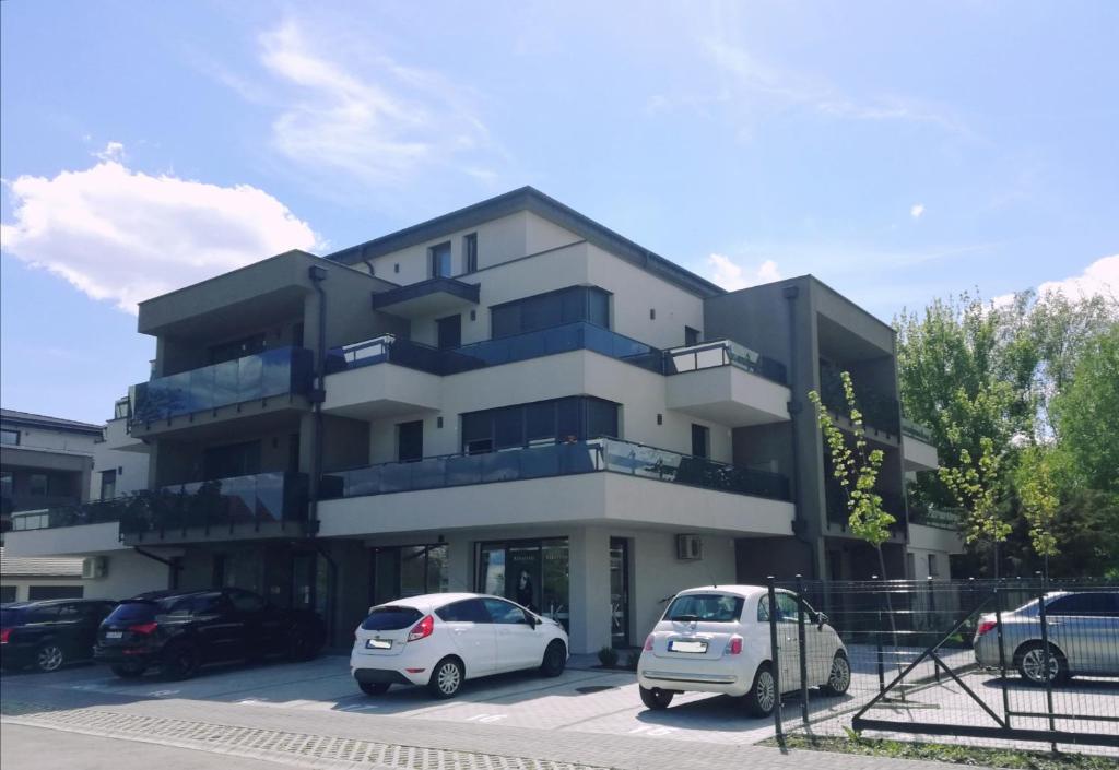 budynek z dwoma samochodami zaparkowanymi na parkingu w obiekcie Lakeside Family & Studio Apartments w mieście Keszthely