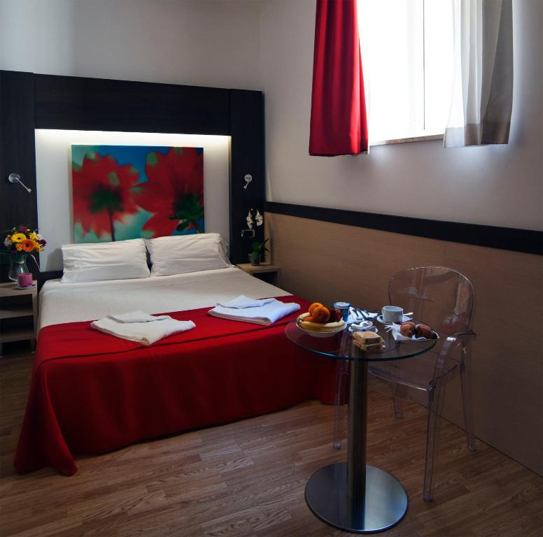 a bedroom with a bed with a red blanket and a table at Hotel Louisiana in Rome