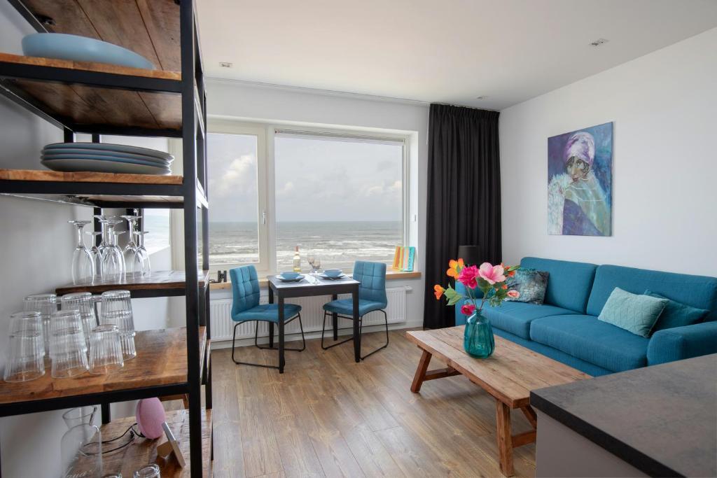 een woonkamer met een blauwe bank en een tafel bij Costa in Zandvoort