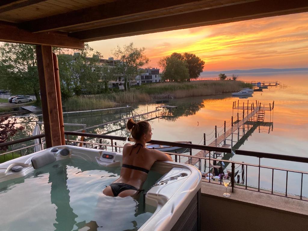 a woman in a hot tub on a balcony with a sunset at Royal Mediterran in Siófok