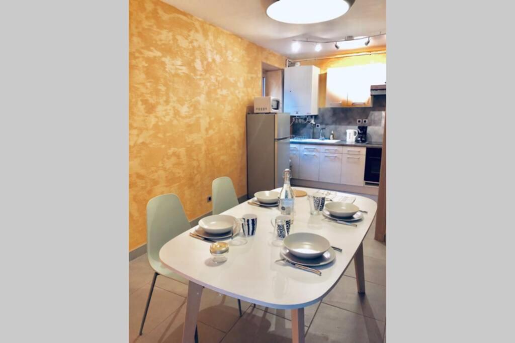 uma mesa branca e cadeiras numa cozinha em F3 - NEUF - 4/6 p - lits King size - Wifi - Cour em Le Puy-en-Velay